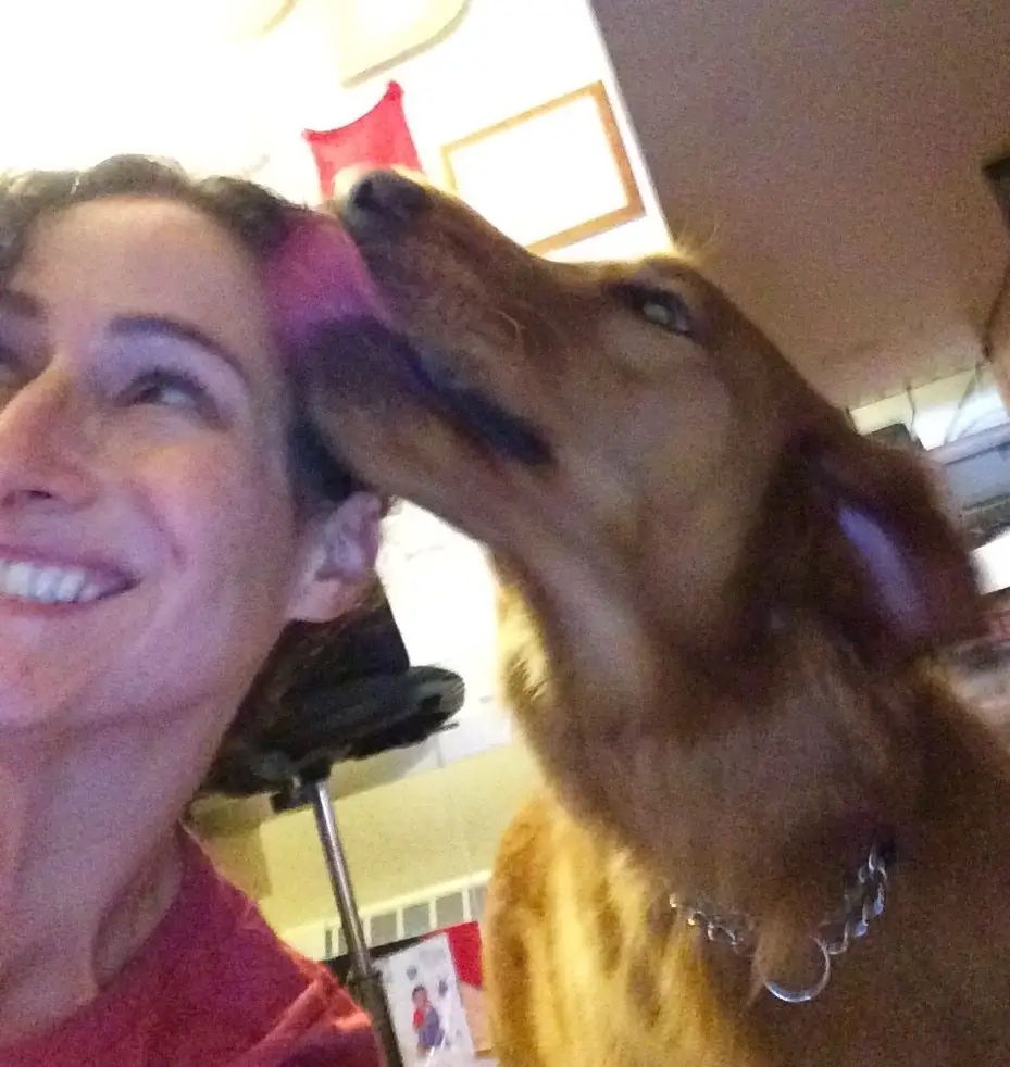 Simona smiling as a dog licks her face